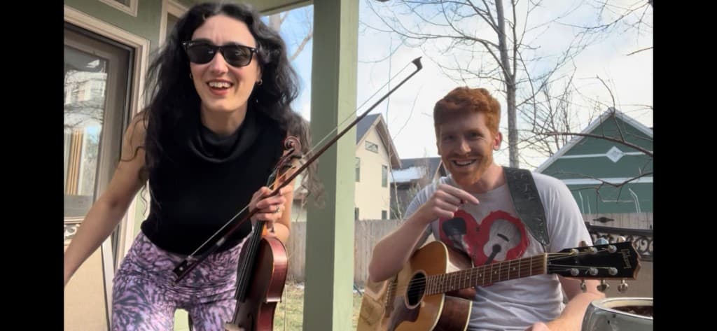 Sarah and Ben rehearsing with violin and guitar on a porch